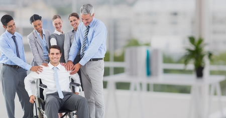 Business executives consoling their colleague sitting on wheelchair at officeの写真素材