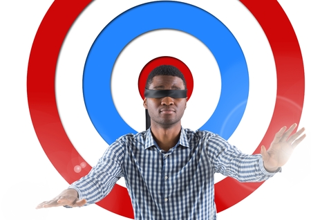 Digital composite conceptual image of male executive with black band on eyes against standing archery boardの写真素材