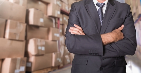 Mid section of businessman standing with his arms crossed at warehouseの写真素材