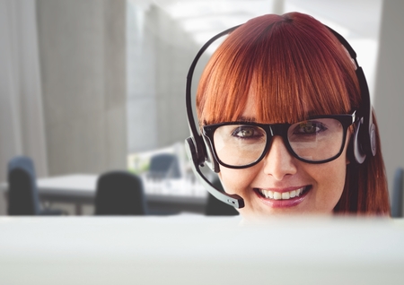 Portrait of a happy woman talking on headset in customer service officeの写真素材