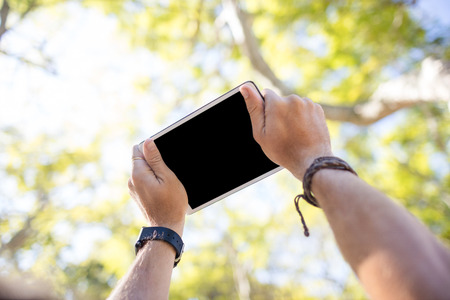 Close-up of man hands using digital tablet in parkの写真素材