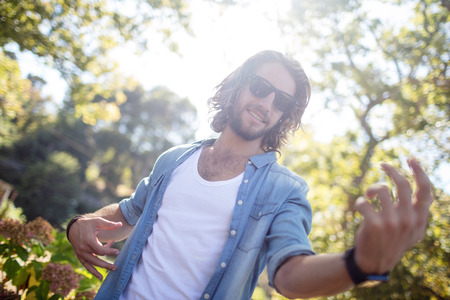 Happy man playing air guitar in park on a sunny dayの写真素材