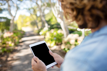 Man standing in park using digital tabletの写真素材