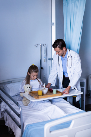 Doctor serving breakfast to girl in hospitalの写真素材