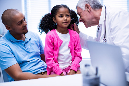 Doctor examining patients ear with otoscope in clinic