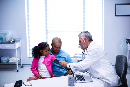 Doctor checking patient blood pressure in clinicの写真素材