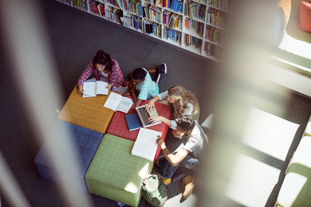 Overhead view of attentive students studying in library at schoolの写真素材
