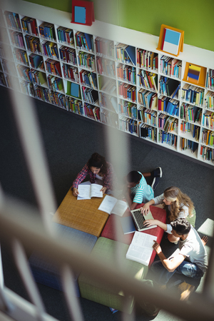 Overhead view of attentive students studying in library at schoolの写真素材