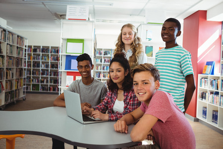 Portrait of confident students sitting at desk in library