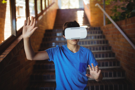 Schoolboy using virtual reality headset on staircase at school
