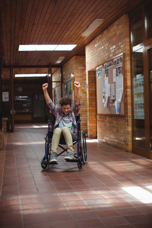 Excited disabled schoolboy on wheelchair in corridor at schoolの写真素材