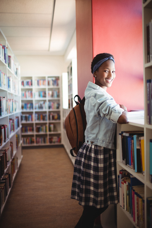 Portrait of schoolgirl reading book in library at schoolの写真素材