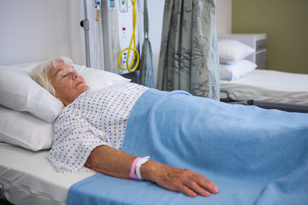 Senior patient lying on bed in hospitalの写真素材
