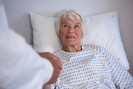 Doctor examining senior patient in ward at hospitalの写真素材