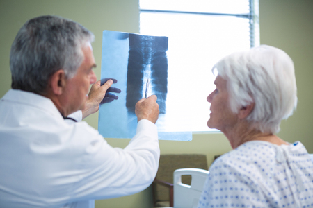 Doctor discussing x-ray report with senior patient in hospitalの写真素材