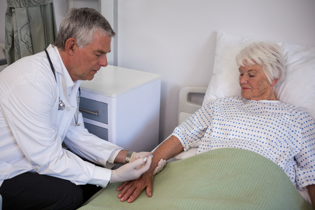 Doctor giving injection to senior patient in hospitalの写真素材
