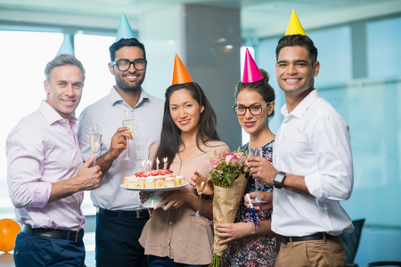 Portrait of smiling business colleagues celebrating birthday in officeの写真素材