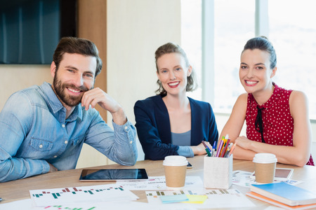 Portrait of smiling business executives sitting together in conference room at officeの写真素材