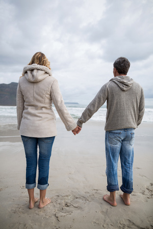 Rear view of standing with couple holding hands on the beachの写真素材