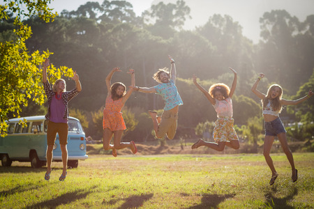 Friends jumping in excitement in park on a sunny day