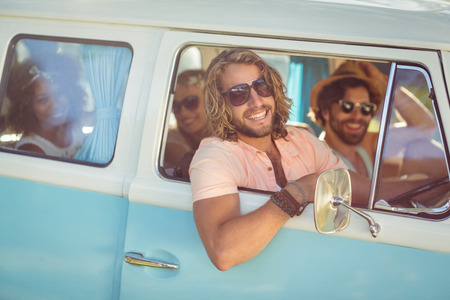 Smiling man looking out of camper van window on a sunny dayの写真素材