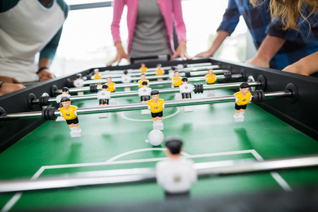 Mid section of executives playing table football in officeの写真素材
