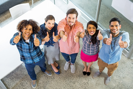 High angle view of happy executives showing thumbs up in office