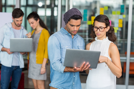Attentive executives using laptop in officeの写真素材