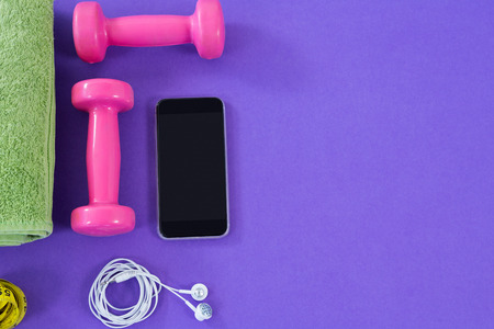 Dumbbells, towel, mobile phone with headphones on purple backgroundの写真素材