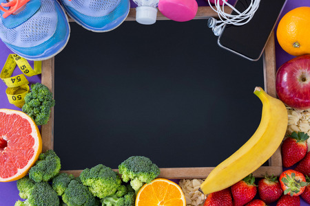 Slate surrounded with fitness accessories and various fruits and vegetablesの写真素材