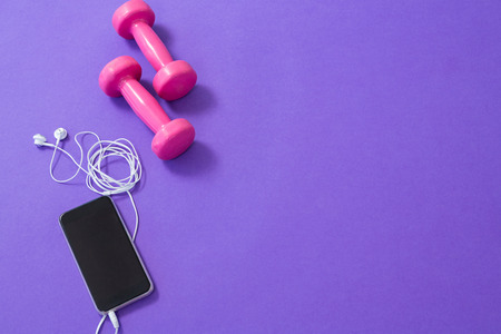 Dumbbells, mobile phone with headphones on purple backgroundの写真素材