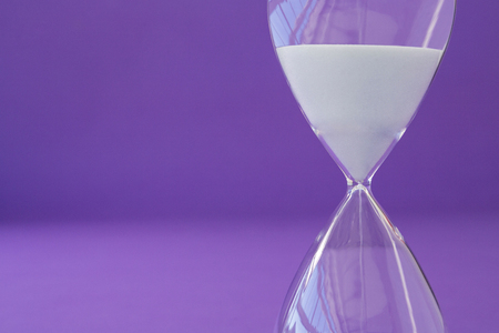 Close-up of hourglass against purple backgroundの写真素材
