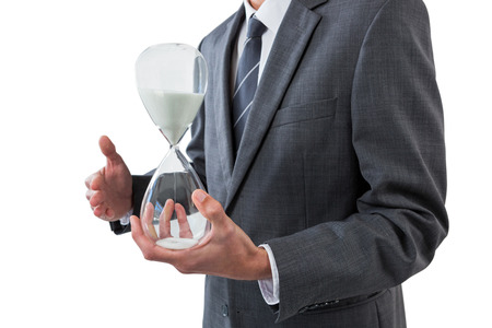 Mid section of businessman holding hourglass against white background