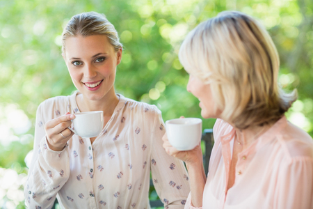 Smiling friends enjoying coffee together at restaurantの写真素材