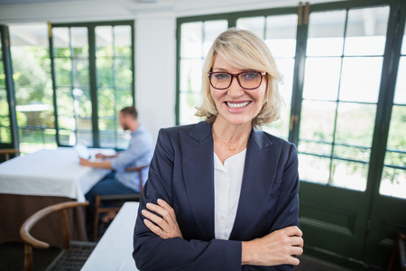Portrait of businesswoman standing with arms crossed in a restaurantの写真素材