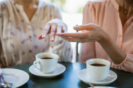 Mid section of woman showing engagement ring to her friend at restaurantの写真素材