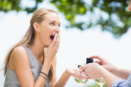 Man proposing to woman offering engagement ring in a restaurantの写真素材