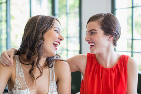 Happy friends smiling while looking at each other in the restaurantの写真素材