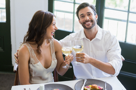 Happy couple toasting wine glasses in the restaurantの写真素材