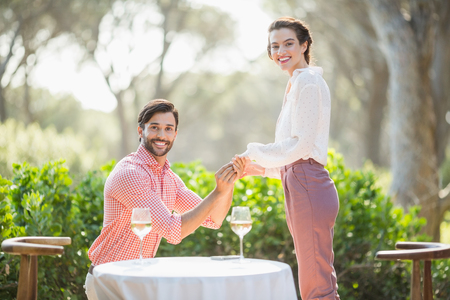 Portrait of man proposing a woman with a ring on his knee in the restaurantの写真素材
