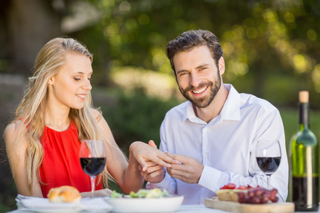 Happy man putting a ring on womans finger in the restaurantの写真素材