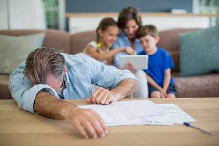 Worried man calculating bills in living room at homeの写真素材