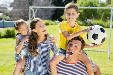 Portrait of smiling parents carrying their two children on their shoulders in the parkの写真素材