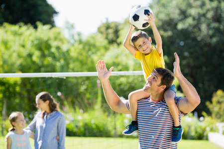 Happy family playing football in the park on a sunny dayの写真素材
