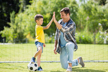 Father and son giving high five in the park on a sunny dayの写真素材