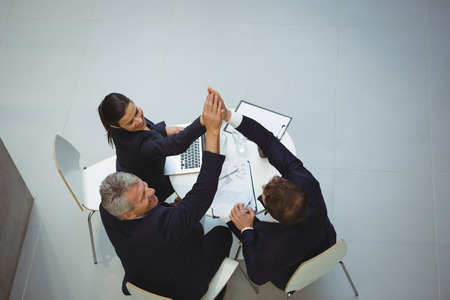 Businesspeople giving a high five to each other in office