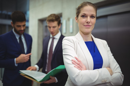 Portrait of beautiful businesswoman standing with arms crossed in officeの写真素材