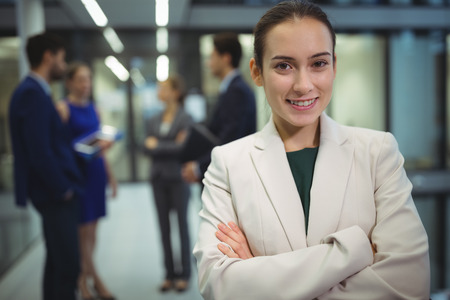 Portrait of smiling businesswoman standing with arms crossed in officeの写真素材