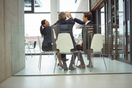 Businesspeople giving a high five to each other in officeの写真素材