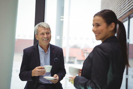 Happy businessman man and businesswoman having coffee in officeの写真素材